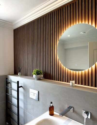 Modern bathroom vanity with wood slatted feature wall and LED mirror in Derby