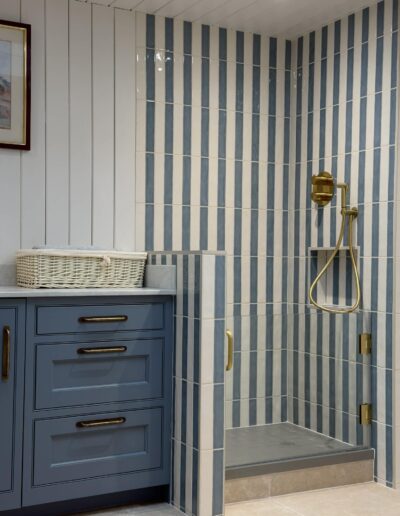 Blue striped tile walk-in shower with brass fittings in Derby bathroom